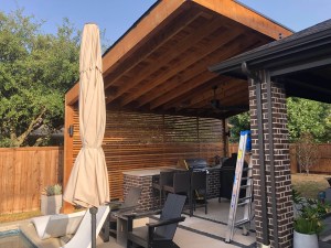 An Outdoor Living Specialist created a backyard covered patio with a grill and umbrella, enhancing the home with a stylish home addition.