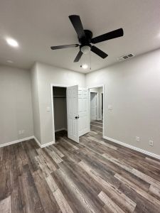 A vacant room with hardwood floors and a ceiling fan is awaiting customization by a Home Renovations or Custom Home Builder specialist.
