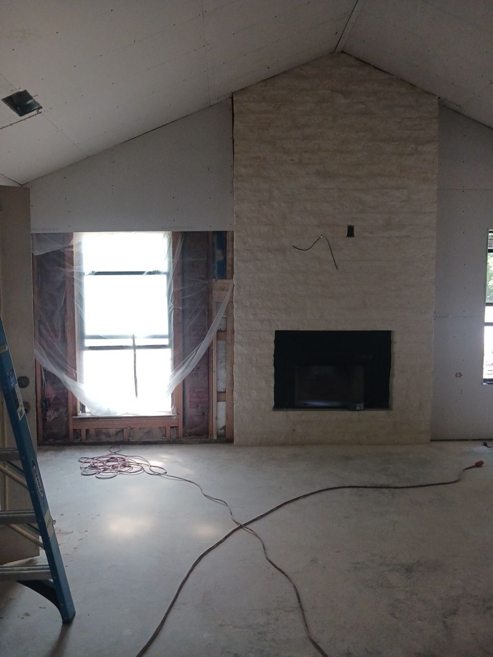 Interior of a room under construction with an unfinished fireplace and a ladder on the side, managed by a General Contractor in McKinney, TX.